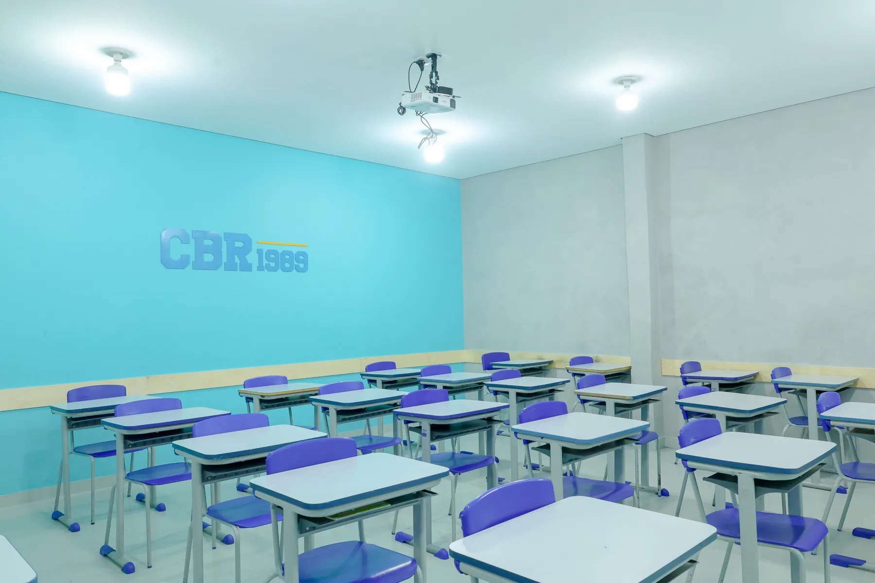 Sala de aula azul turquesa com carteiras organizadas