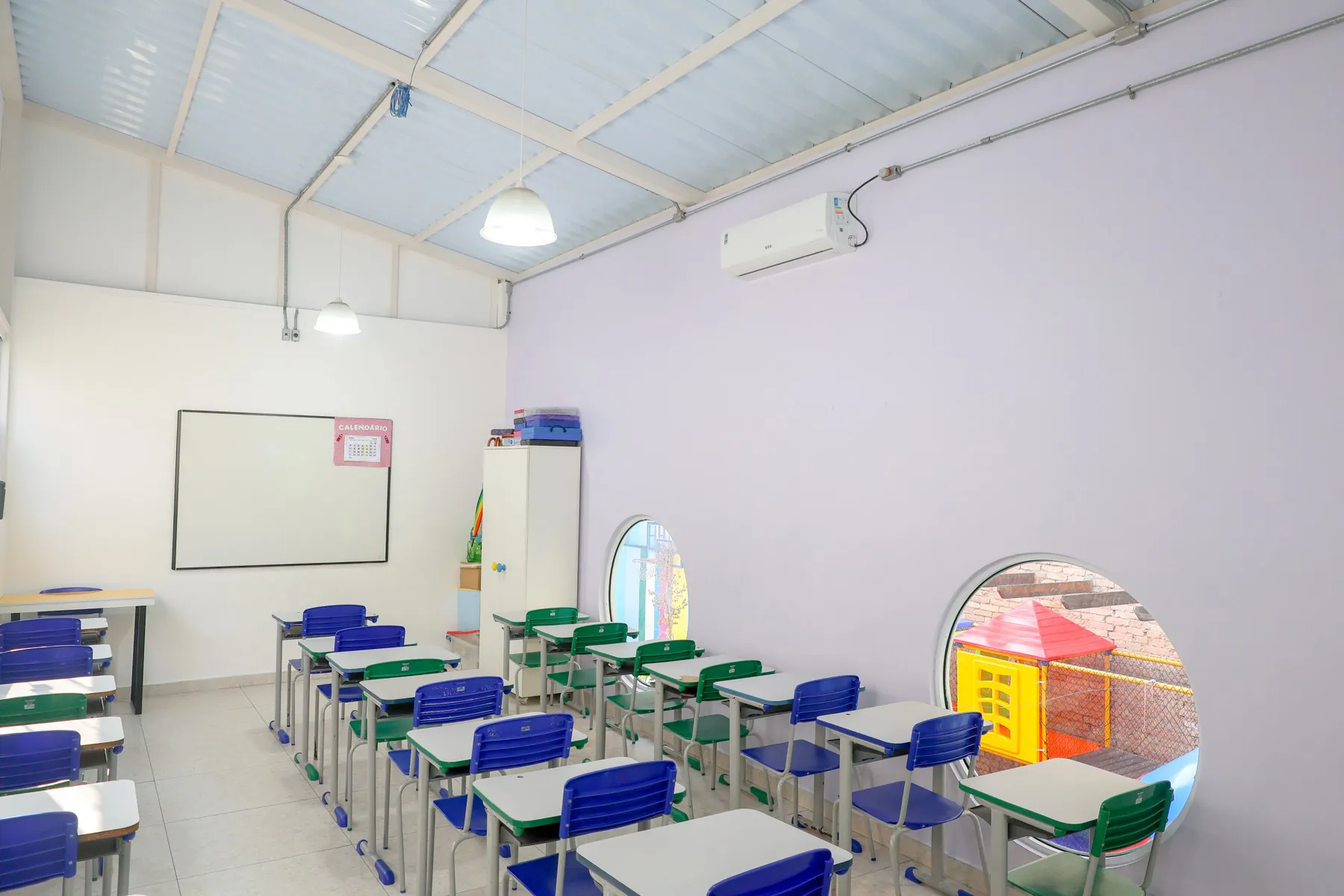 Sala de aula com janelas redondas com vista para o playground